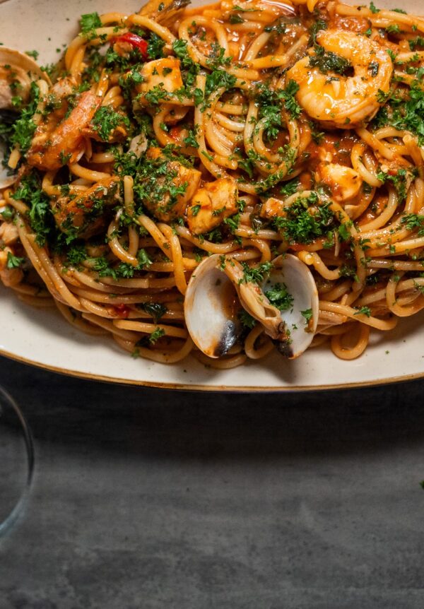 A beautifully plated seafood spaghetti featuring prawns, mussels, and calamari tossed in a rich tomato‑white wine sauce, served with fresh herbs and al dente pasta. Styled with a glass of white wine on the side, this dish captures the warm, modern dining atmosphere of Moonchild Café Bar Bistro in Prahran.