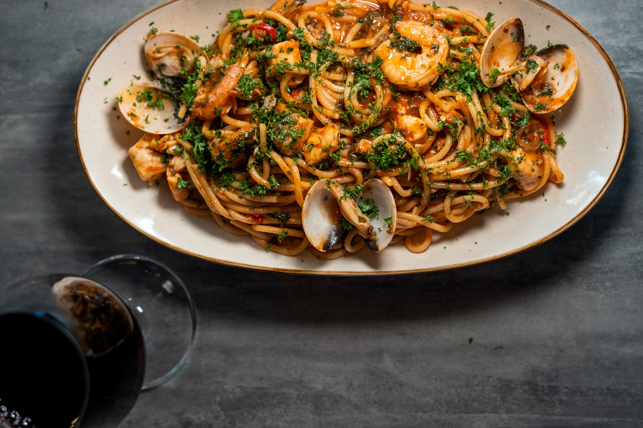A beautifully plated seafood spaghetti featuring prawns, mussels, and calamari tossed in a rich tomato‑white wine sauce, served with fresh herbs and al dente pasta. Styled with a glass of white wine on the side, this dish captures the warm, modern dining atmosphere of Moonchild Café Bar Bistro in Prahran.